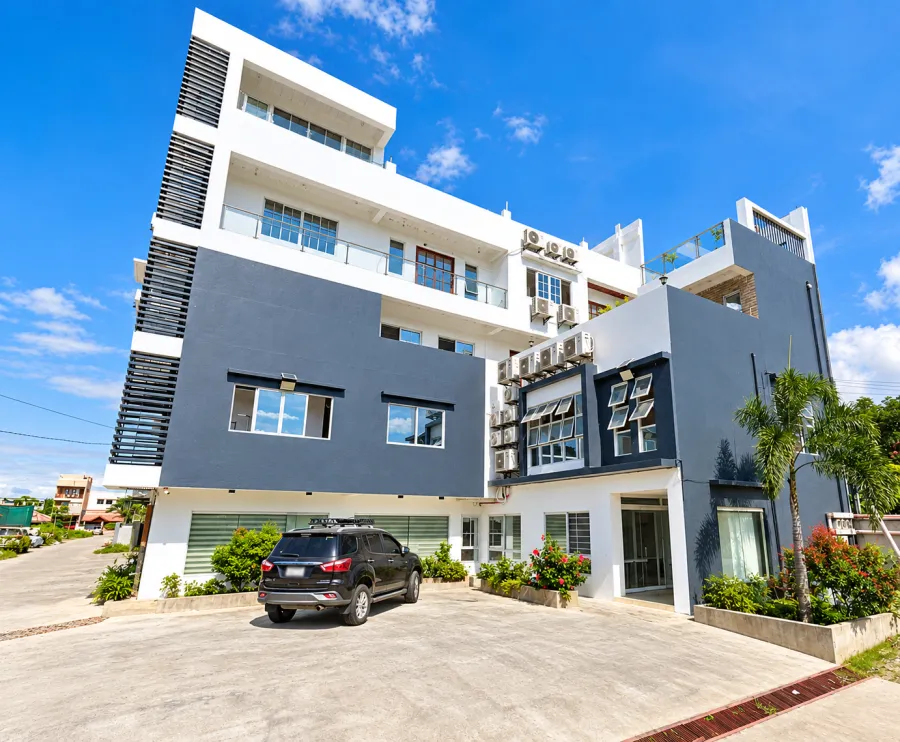 Five-storey white and charcoal commercial building with parking in front, in Leonarda, Tuguegarao City